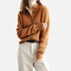 Rust orange cashmere cardigan with ribbed stand collar and folded arms, paired with cream trousers