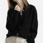 Black cashmere cardigan with a round collar and button placket, cropped view over cream trousers