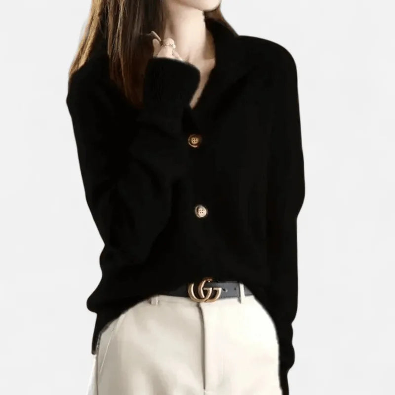 Black cashmere cardigan with notched collar worn open over a gold double-ring buckle belt