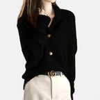 Black cashmere cardigan with notched collar worn open over a gold double-ring buckle belt