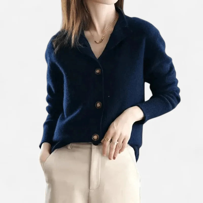 Model wearing a knitted cashmere cardigan with ribbed cuffs, hand raised to the collar