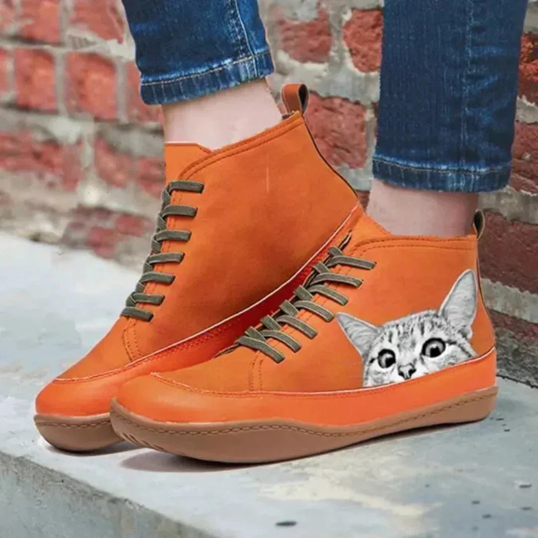Close-up of orange boots worn with rolled jeans, showing the tabby cat detail, stitched panels and rubber sole