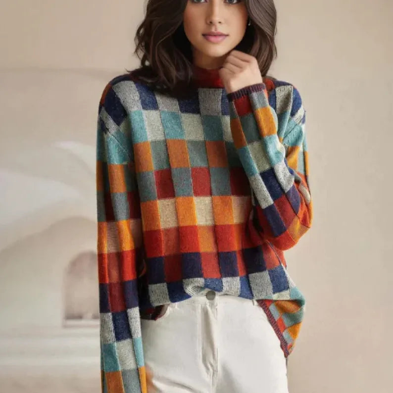 Woman wearing a colourful checked knit polo neck jumper with long sleeves, paired with white trousers