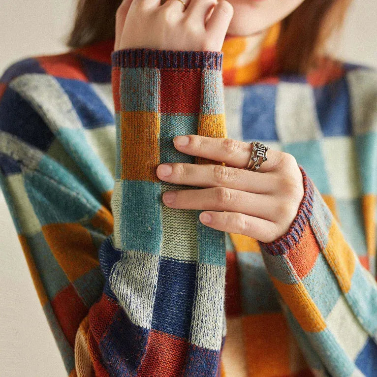 Close-up of hands resting on the ribbed cuff, showing the knit texture and multicolour check design