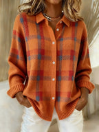 Close-up of orange checked knit shacket with white button fastenings and collared neckline, worn over white trousers