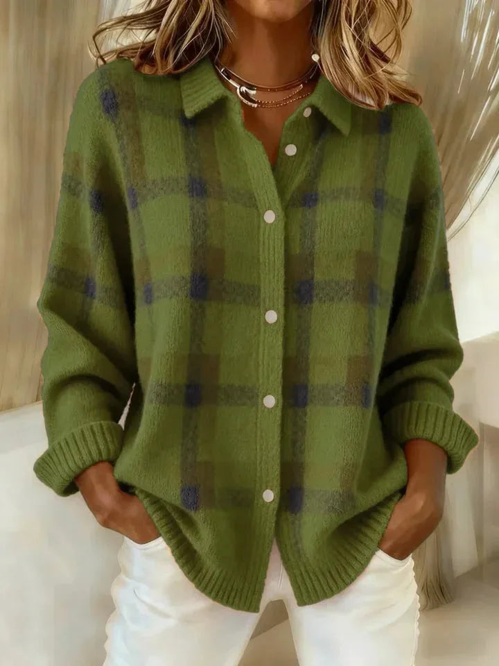 Green and navy checked knit overshirt with ribbed cuffs and collar, close-up front view against white trousers