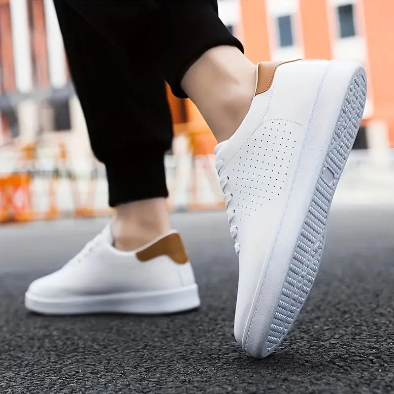 Close-up of a white trainer with tan heel tab worn on foot mid-step on a city street