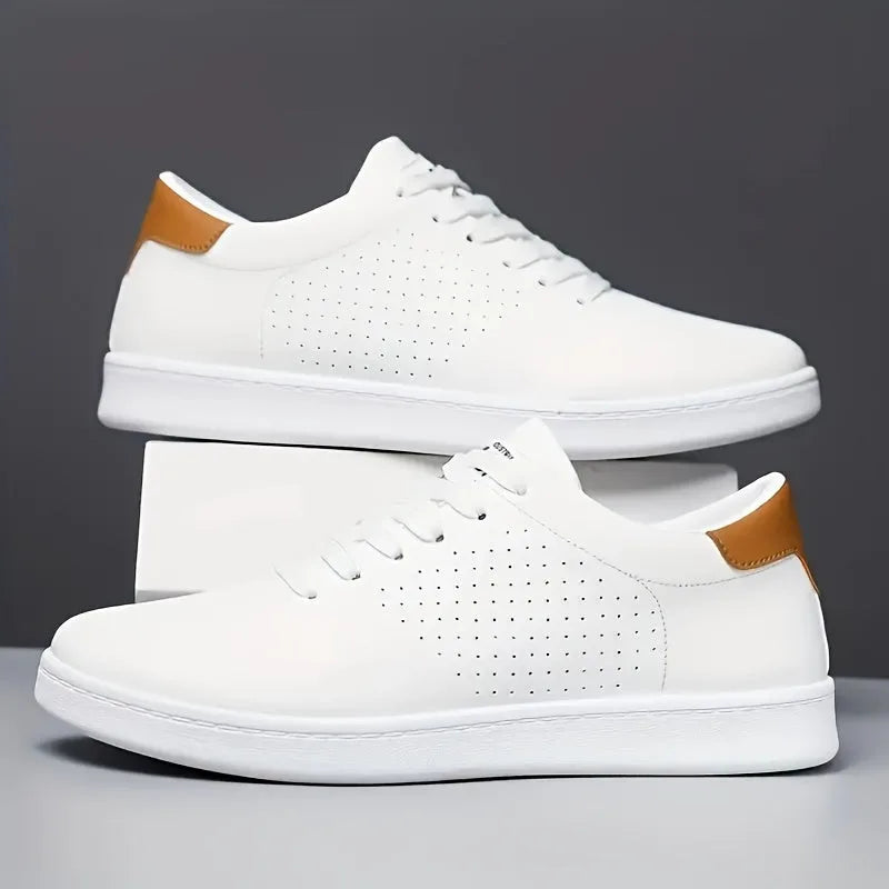 Pair of white trainers with tan heel trim and perforated detailing stacked on a white box