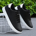 Pair of black trainers with white heel trim resting on a white wire stool outdoors