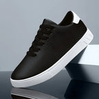 Single black trainer with white heel patch and perforated toe balanced on a glossy block