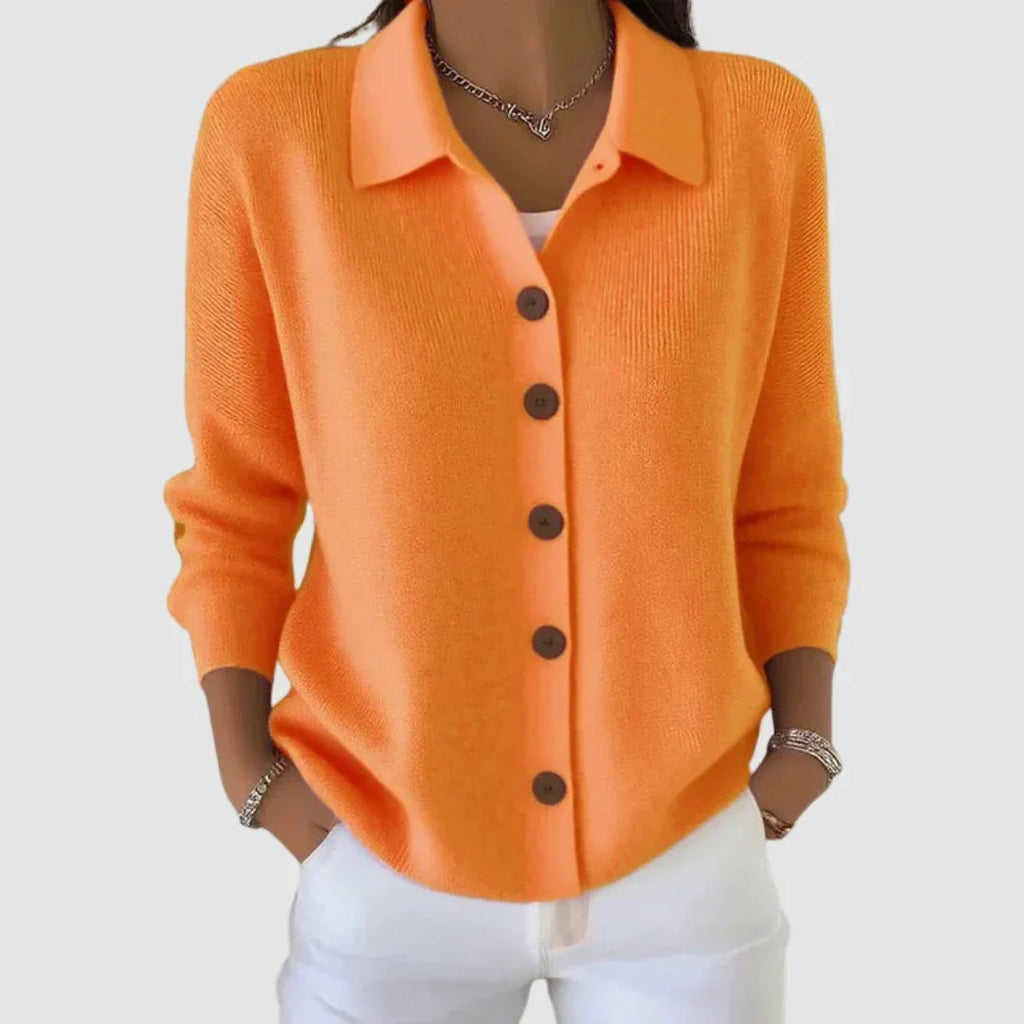 Front view of orange ribbed knit cardigan with collar, wooden buttons and long sleeves, styled with white jeans