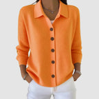 Front view of orange ribbed knit cardigan with collar, wooden buttons and long sleeves, styled with white jeans