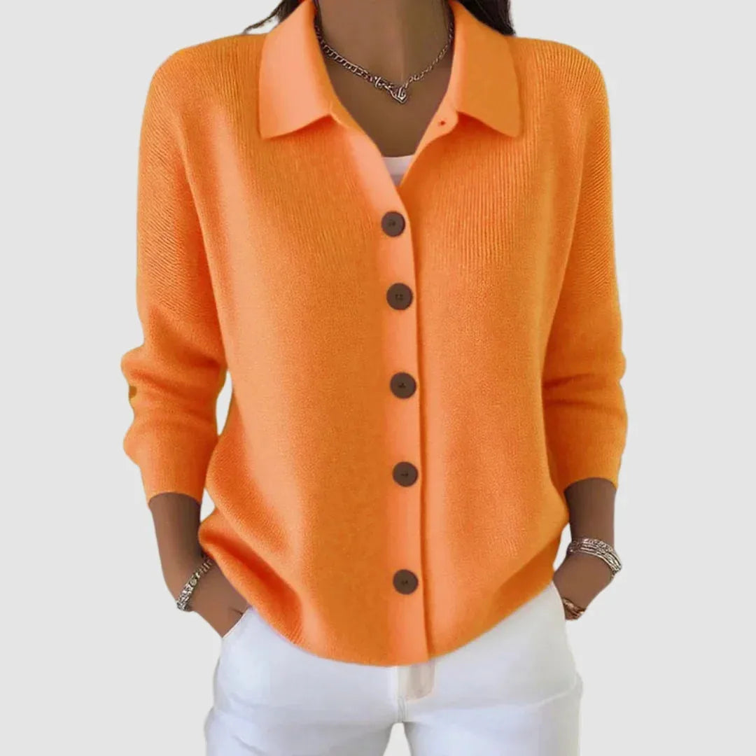Front view of orange ribbed knit cardigan with collar, wooden buttons and long sleeves, styled with white jeans