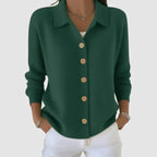 Dark forest green cardigan with collar and light wooden buttons, close-up showing ribbed knit texture
