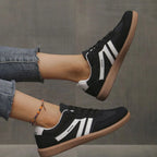 Action shot of black and white trainers with gum sole shown mid-step