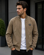 Front view of a taupe brown corduroy bomber jacket with silver front zip and Free Spirit chest patch.