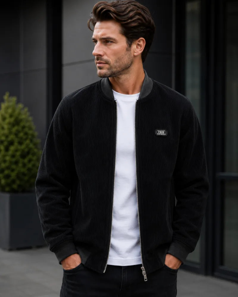 Black corduroy bomber jacket with contrast grey ribbed collar, zipped fully over a white tee.