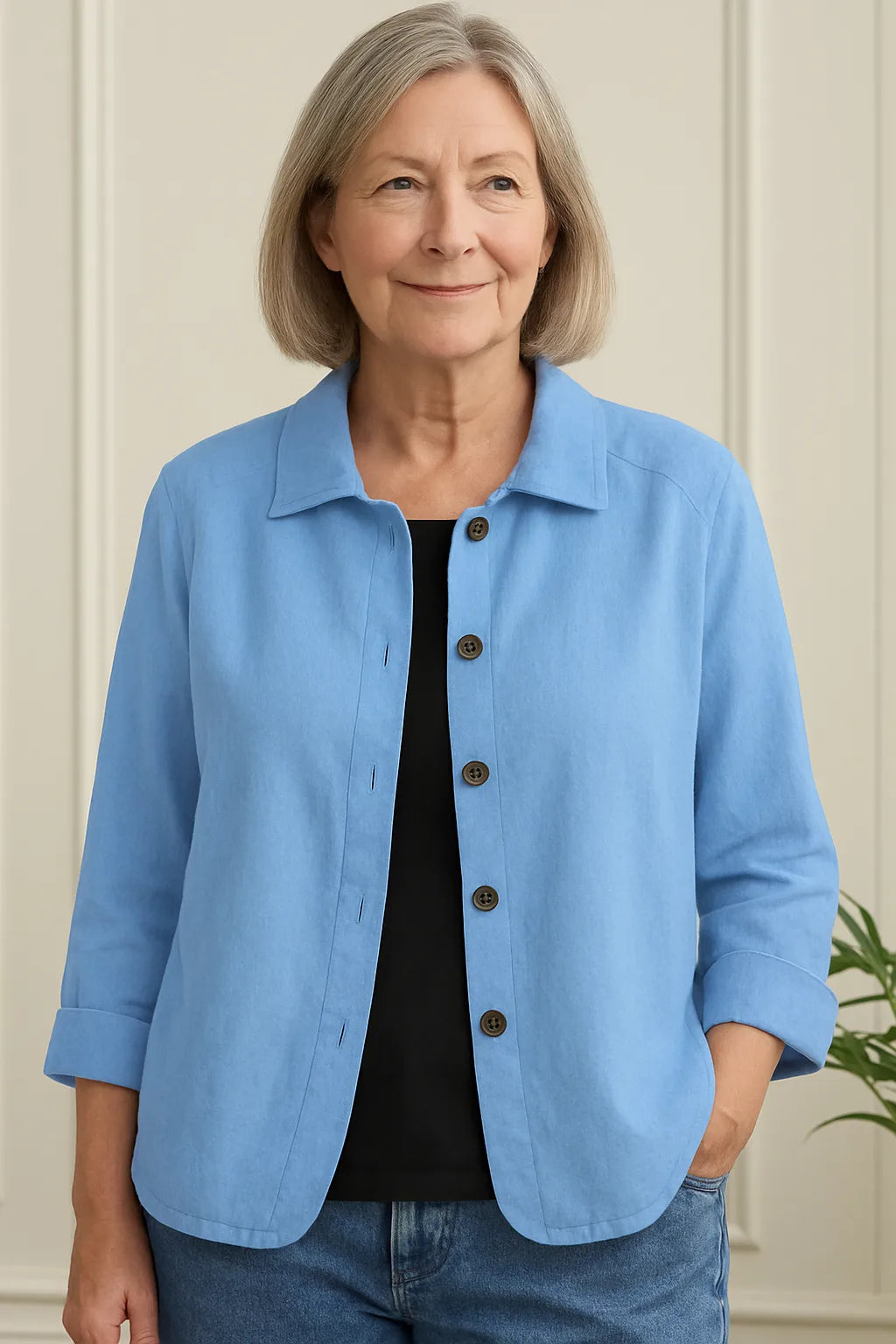 Woman wearing an open light blue cotton-linen shirt jacket with three-quarter sleeves over a black top and jeans