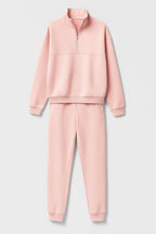 Flat lay of the pink half-zip sweatshirt and jogger trousers set on a plain background
