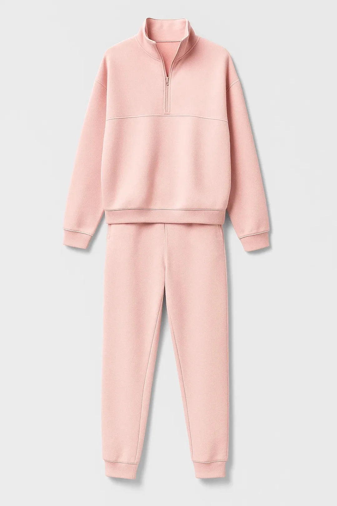 Flat lay of the pink half-zip sweatshirt and jogger trousers set on a plain background
