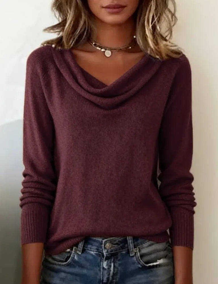 White cowl neck jumper worn over denim jeans with a silver watch on the wrist