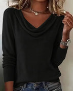 Dark purple cowl neck jumper worn with hands resting at the waist over denim trousers