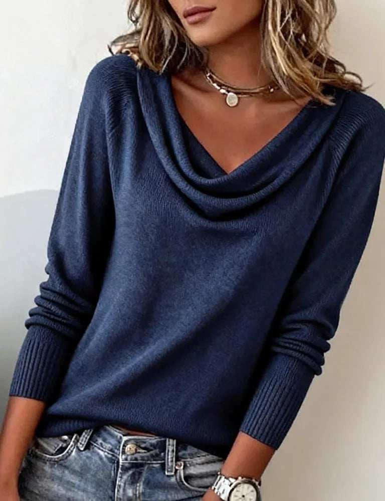 Navy blue cowl neck jumper worn with ripped denim, soft knit texture visible across the shoulders and chest