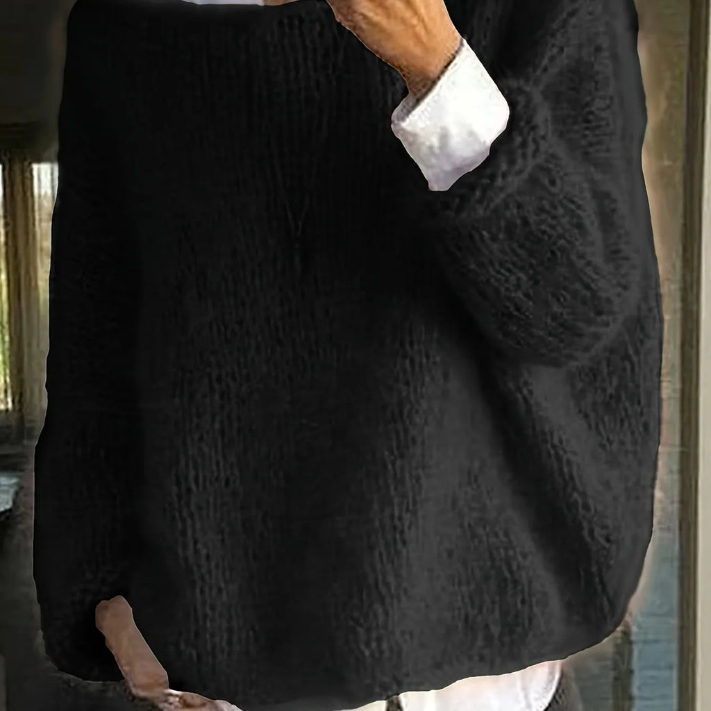 Close-up of a black oversized knitted jumper showing its fuzzy textured knit and long sleeve