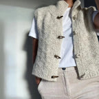 Side view of the cream knitted gilet with high stand collar, wooden toggles, and diamond stitch pattern