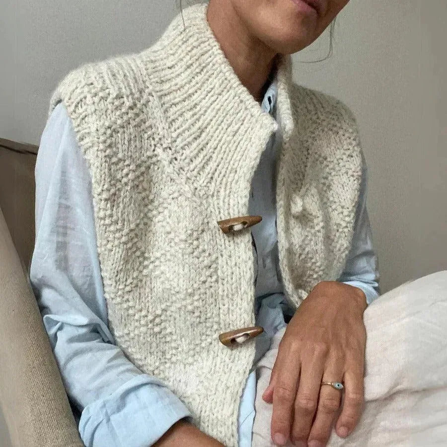 Cream textured knit gilet layered over a light blue shirt, showing the ribbed collar and hem detail