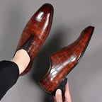 Overhead view of a pair of dark brown croc-embossed loafers being worn, showing the slip-on fit at the ankle