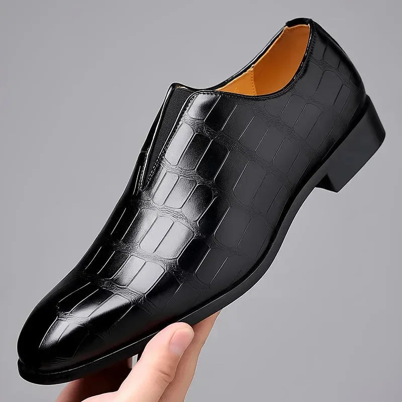 Single dark brown croc-embossed loafer held in hand, showing the pointed toe and slip-on elastic gusset