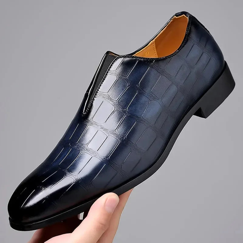 Single black croc-embossed loafer held in hand, showing the glossy finish and tan interior lining