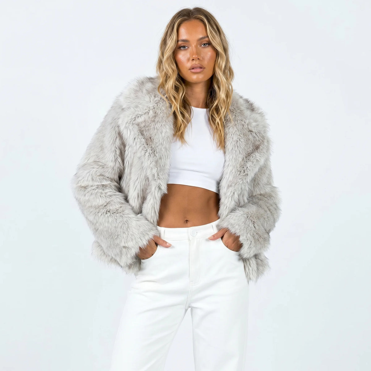 Front view of cropped faux fur jacket in rice grey, worn open over a white crop top and white jeans