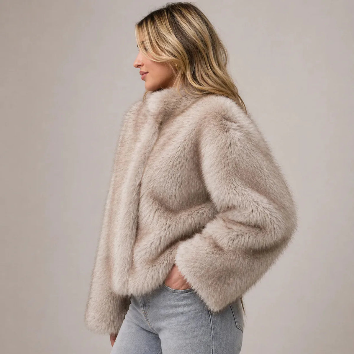 Side profile showing the plush texture and shawl collar of the taupe faux fur cropped jacket
