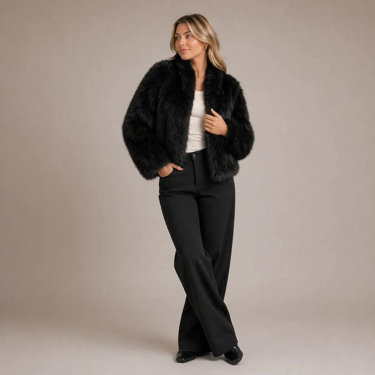 Woman wearing a black faux fur cropped jacket with shawl collar over black wide leg trousers