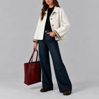 Woman wearing a cropped white boxy jacket with checked cuff lining over a black jumper and wide-leg jeans, front view