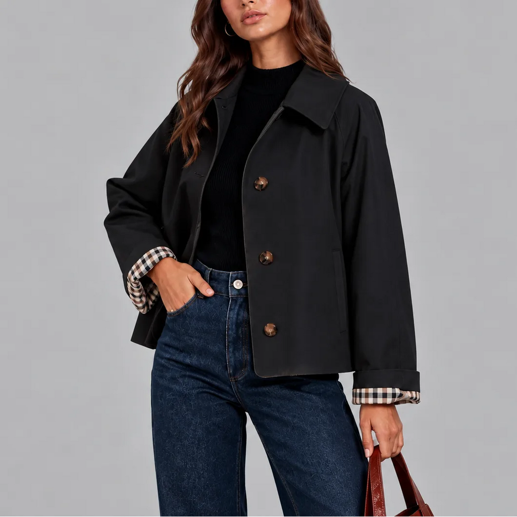 Close-up of the black cropped jacket showing tortoiseshell buttons, wide collar and checked lining at the cuff