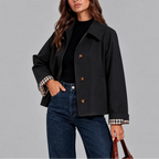 Close-up of the black cropped jacket showing tortoiseshell buttons, wide collar and checked lining at the cuff
