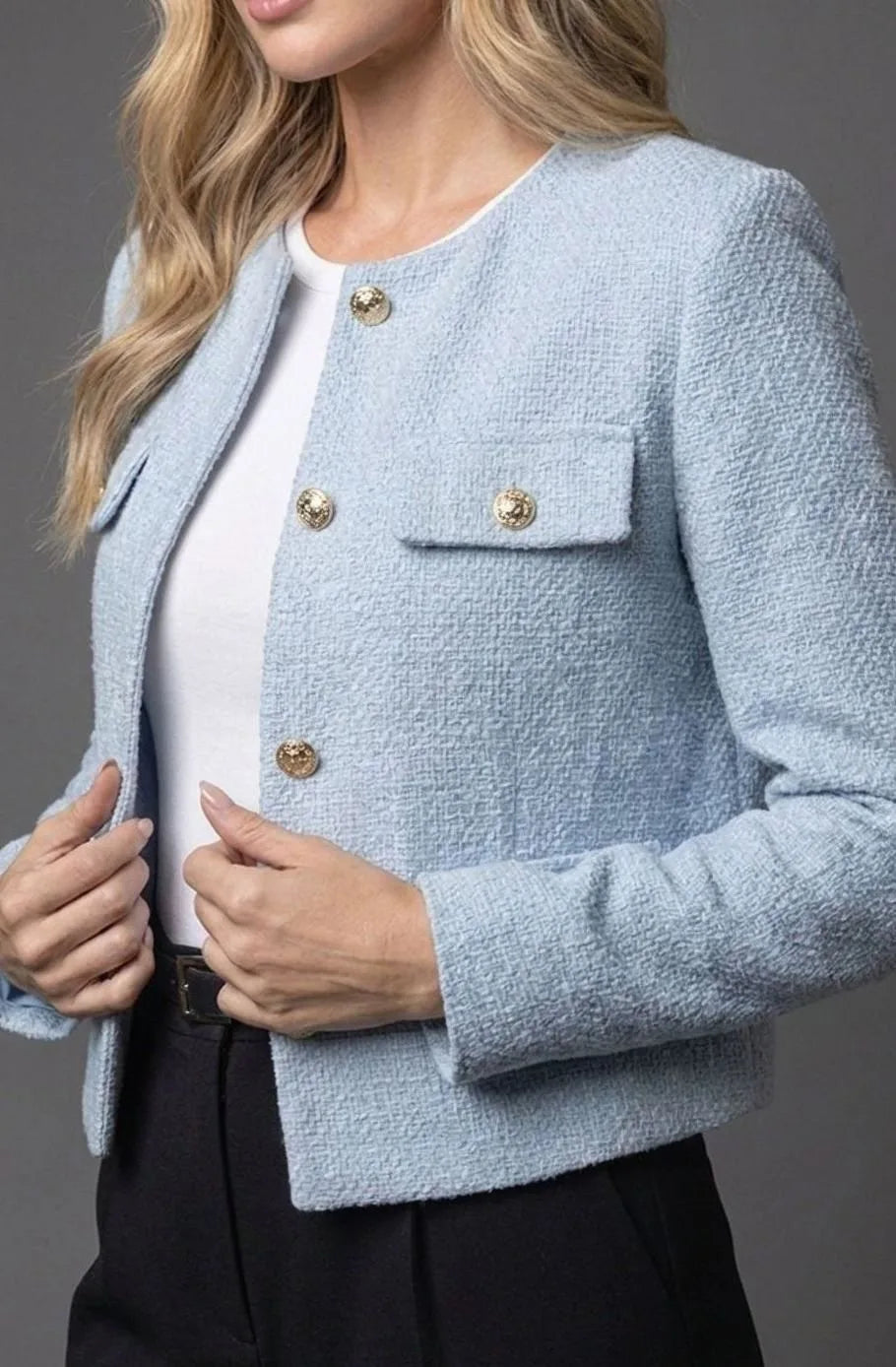 Close-up of the pale blue tweed jacket showing gold button detailing and a flap pocket on the chest