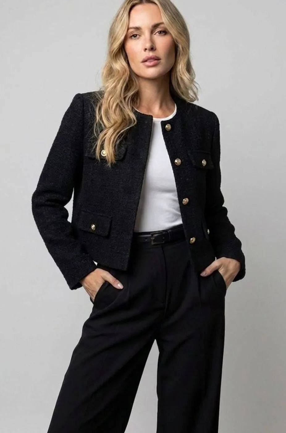 Model in a black textured tweed cropped jacket, collarless, worn open over a white top with black trousers