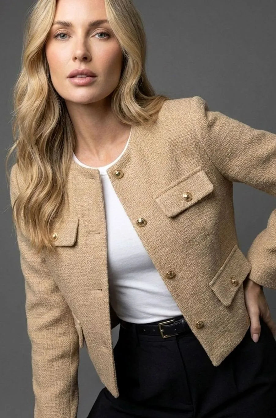 Close-up of a camel tan tweed cropped jacket showing gold buttons and structured flap pockets