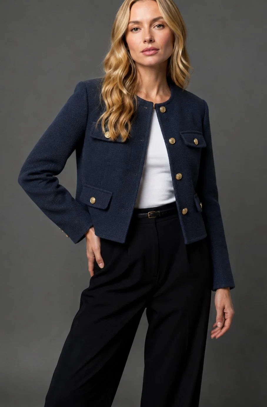 Model wearing a navy blue tweed cropped jacket with gold buttons, styled with a white top and black trousers