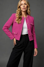 Woman in a bright pink fuchsia tweed cropped jacket with gold button fastening and flap pockets