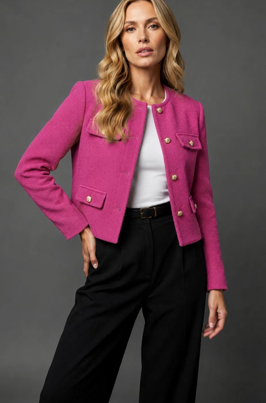 Woman in a bright pink fuchsia tweed cropped jacket with gold button fastening and flap pockets