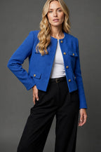 Model wearing a cobalt blue textured tweed cropped jacket with gold buttons over a white top