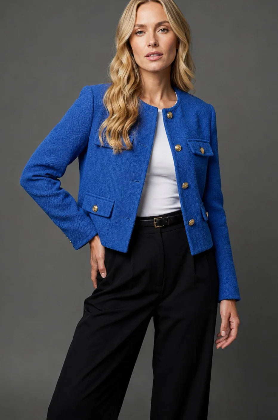 Model wearing a cobalt blue textured tweed cropped jacket with gold buttons over a white top