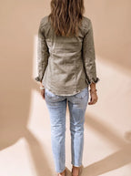 Back view of the olive green denim jacket showing its slightly fitted shape and raw hem paired with light wash jeans