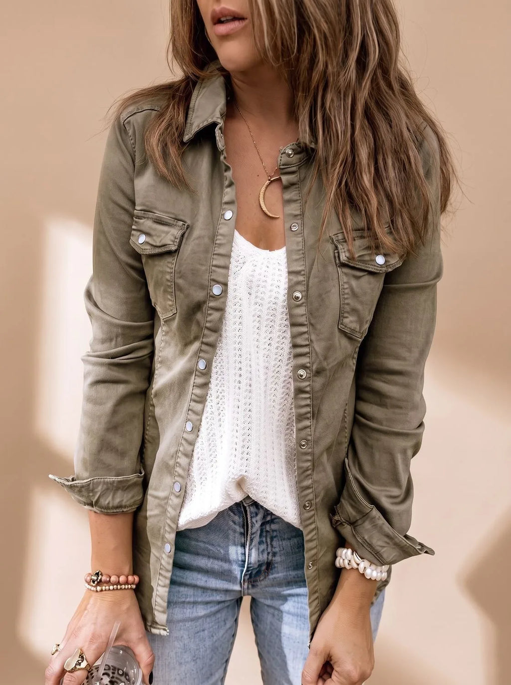 Angled front view of the olive green denim jacket highlighting the snap button placket and rolled-up sleeves