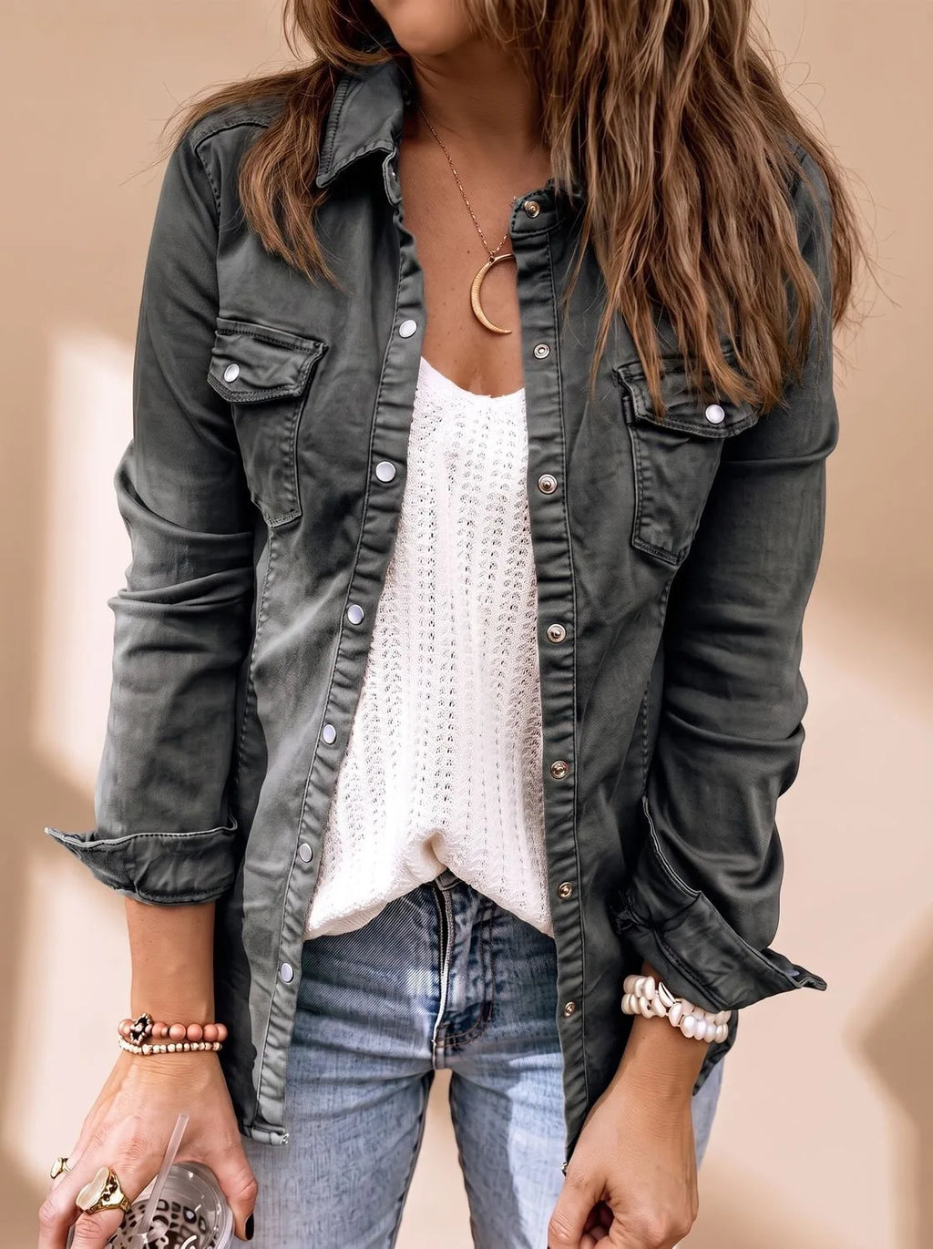Close-up of the same style jacket in a dark charcoal grey denim wash worn over a white knit top